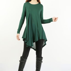 May include: A long-sleeved, dark green tunic top with a high, rounded neckline and a flowing, asymmetrical hemline. The top is made of a soft, stretchy fabric and is perfect for layering.