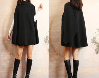 May include: A black wool cape with a high collar and a curved hemline. The cape is lined with a black fabric and has a simple design.