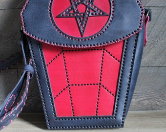 May include: A black leather crossbody bag shaped like a coffin with a red pentagram design on the front flap. The bag has a red interior and black stitching.