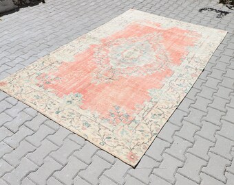 May include: A vintage rug with a peach-coloured centre and a cream-coloured border. The rug has a floral pattern and is in good condition.