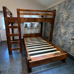 Op de afbeelding: Een houten stapelbed met een warme, gebeitste afwerking. Het heeft een ladder voor het bovenste bed en een lattenbodem. Het ontwerp is rustiek en stevig, geschikt voor een kinder- of logeerkamer. Afmetingen in centimeters.