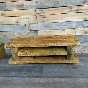 Op de afbeelding: Een rustieke houten salontafel met twee planken. De tafel is gemaakt van lichtbruin hout en heeft een natuurlijke, verweerde uitstraling. De tekst "Bespoke Carpentry" is zichtbaar op de bovenkant van de tafel.