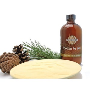 May include: A brown glass bottle labelled "Pollen de pin" with a gold and brown label, pine needles, pine cones, and a round, light yellow powder. The bottle has a dark cap against a white background.