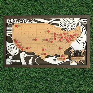 May include: A wooden map of the United States with red baseballs marking locations. The map is framed in brown wood and includes a baseball-themed design with the text "NEWMAN FAMILY".