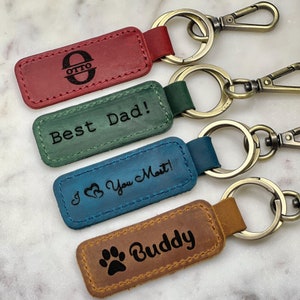 four leather keychains with the words best dad and a dog's paw