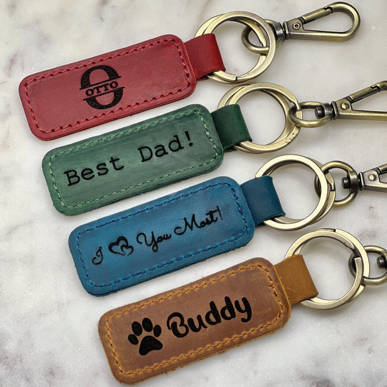 four leather keychains with the words best dad and a dog's paw