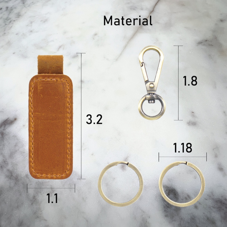 May include: A brown leather key chain with a metal clasp and two metal rings. The key chain measures 3.2 inches in length, 1.1 inches in width, and 1.8 inches in height.
