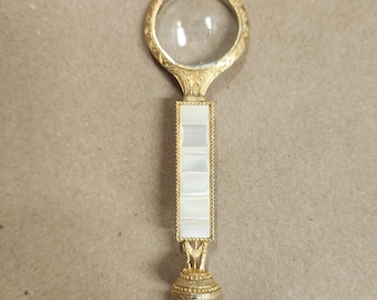 Lupa vintage adornada con nácar dorado, década de 1920. Mide 4" de largo.