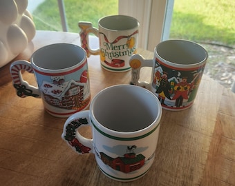 May include: Four ceramic Christmas mugs with festive designs. One mug has a candy cane handle, another says "Merry Christmas", and the others feature winter scenes. The mugs are white with colorful illustrations and are set on a wooden surface.