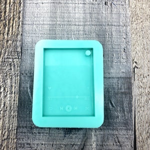 Puede incluir: Un molde de silicona azul turquesa con forma de reproductor de m&uacute;sica con un coraz&oacute;n, botones de reproducci&oacute;n, pausa y avance. El molde tiene un peque&ntilde;o c&iacute;rculo en la parte superior para un llavero.