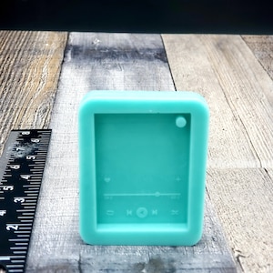 May include: A teal blue silicone mold shaped like a music player with buttons for play, pause, and skip. The mold has a heart icon, a slider, and a plus sign.