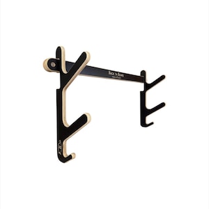 May include: Black and natural wood-toned wall-mounted rack for surfboards. The rack features a horizontal bar with the text "RACK TA BOARD" and several curved arms designed to hold surfboards. Made in France.