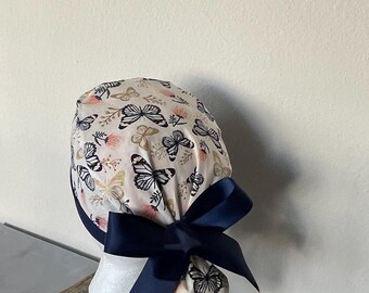 Touca cirúrgica feminina com abertura para rabo de cavalo, estampa de borboletas e flores da primavera, ajustável com botões.