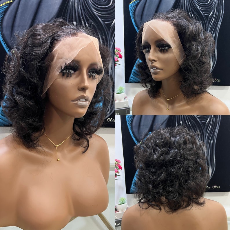 May include: A black curly human hair wig with a lace front. The wig is styled in a short bob with loose curls. The wig is on a mannequin head.