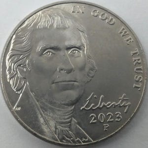 Może przedstawiać: Srebrna moneta z portretem Thomasa Jeffersona. Moneta zawiera napisy "IN GOD WE TRUST" i "LIBERTY 2023". Litera "P" jest widoczna pod datą.