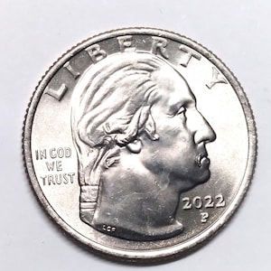 May include: A close-up of a United States quarter coin. The coin features a profile of George Washington, the text "LIBERTY" at the top, and the year "2022" below the profile. The words "IN GOD WE TRUST" are also visible.