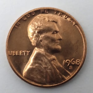 May include: A copper-coloured 1968 United States penny. The obverse features a profile of a man, the word "LIBERTY", and the inscription "IN GOD WE TRUST". The year "1968" and the mint mark "S" are also visible.