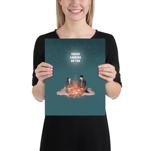 May include: A teal blue poster with a couple sitting by a campfire. The poster has the text "Crash Landing On You" in white.