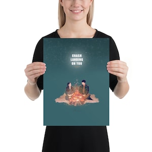 May include: A teal blue poster with a couple sitting by a campfire. The poster has the text "Crash Landing On You" in white.
