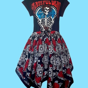 May include: Black t-shirt dress featuring a Grateful Dead skeleton graphic. The dress has a high neckline and a flared skirt with a red rose and paisley pattern. The text "Grateful Dead" is printed across the top.