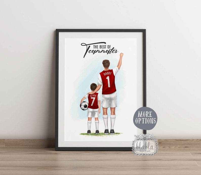 May include: A framed illustration of two people in red soccer jerseys with the text "The Best of Teammates" at the top. The person on the left has the number 7 on their jersey and the person on the right has the number 1 on their jersey. The person on the right is raising their right arm in the air. The illustration is set against a blue and white background.