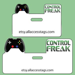 以下が含まれることがあります： 黒いゲームコントローラーのグラフィックと「CONTROL FREAK」の文字が入った、2つの白い長方形のタグ。各タグの下部には、ウェブサイトのアドレスetsy.allaccesstags.comが印刷されています。背景は薄い緑色です。
