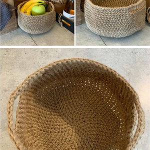 May include: A brown, crocheted, jute basket with two handles. The basket is empty and sitting on a light gray surface.