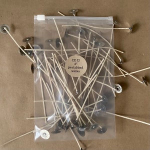 May include: A clear plastic bag filled with 6 inch pre-tabbed candle wicks. The bag has a label that reads "CD 12 6" pretabbed wicks".