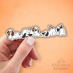 Pode incluir: Uma folha de adesivos com cinco ilustrações de cães dachshund. Os cães têm corpos brancos com marcas marrons ou pretas, em várias poses. Um cão está vestido de fantasma. O fundo é laranja claro.