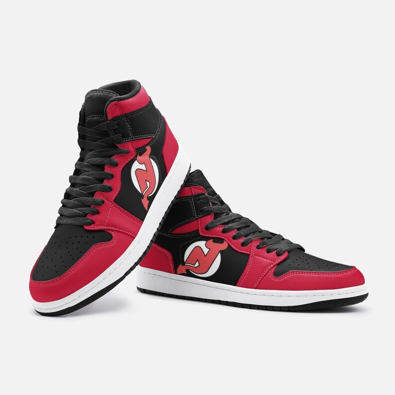 May include: A pair of high-top sneakers with a black and red color scheme. The shoes feature a white sole and a red and white logo on the side.
