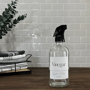 A glass spray bottle filled with white vinegar and water mix