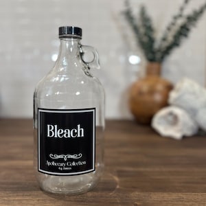 May include: A clear glass bottle with a black label that says "Bleach" and "Apothecary Collection 64 ounces".