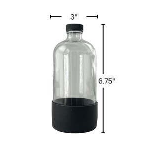 Op de afbeelding: Een heldere glazen fles met een zwarte dop en een zwarte siliconen hoes. De fles is 17,1 cm hoog en 7,6 cm breed.