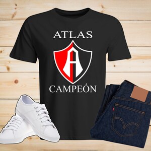 Puede incluir: Camiseta negra con un logo de escudo rojo y blanco que dice "Atlas Campe&oacute;n" en texto blanco.