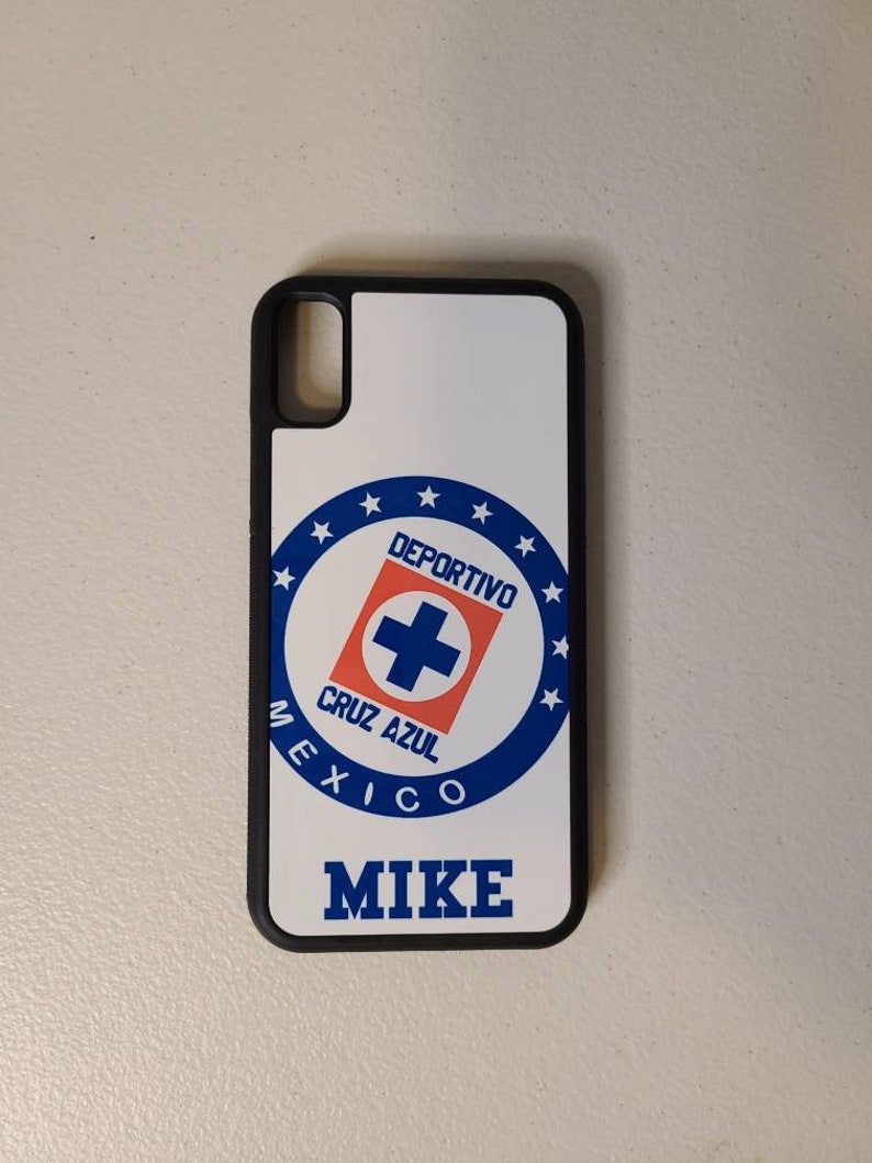 May include: A white phone case with a black border featuring the Deportivo Cruz Azul logo in blue, red, and white. The name "MIKE" is printed in blue below the logo. The case is designed for a smartphone.
