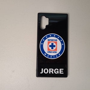May include: Black phone case featuring the Deportivo Cruz Azul logo in blue, white, and red. The case has the name "JORGE" printed in white at the bottom. The case is designed for a specific phone model.