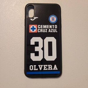 May include: Black phone case featuring the Cemento Cruz Azul logo and the number 30 with the name OLVERA in white. The case has a black border and a blue stripe at the bottom. The case is designed for a smartphone.