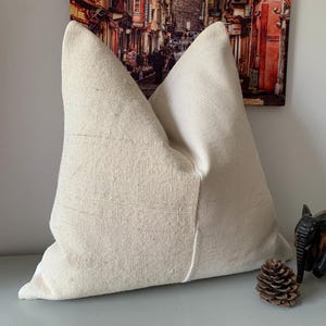 May include: A white linen pillow with a simple, elegant design. The pillow is made of natural materials and has a soft, comfortable feel.