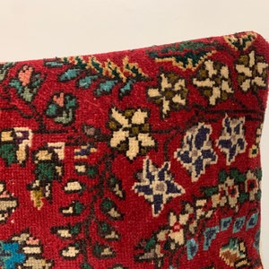 Puede incluir: Funda de coj&iacute;n roja con un patr&oacute;n floral en tonos de blanco, azul, verde y marr&oacute;n. La funda de coj&iacute;n est&aacute; hecha de una tela suave y tejida.