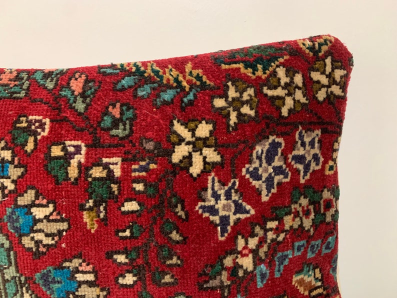 Puede incluir: Funda de coj&iacute;n roja con un patr&oacute;n floral en tonos de blanco, azul, verde y marr&oacute;n. La funda de coj&iacute;n est&aacute; hecha de una tela suave y tejida.