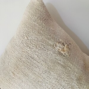 May include: A white throw pillow with a brown and black striped border. The pillow has a textured surface and a small hole in the centre.