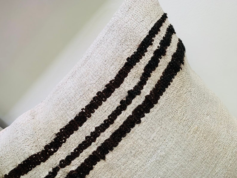 May include: A white throw pillow with three black stripes running diagonally across the front.