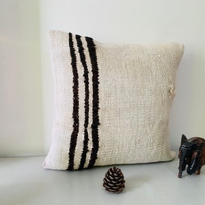 May include: A white throw pillow with black stripes down the side. The pillow is made of a soft, textured fabric.