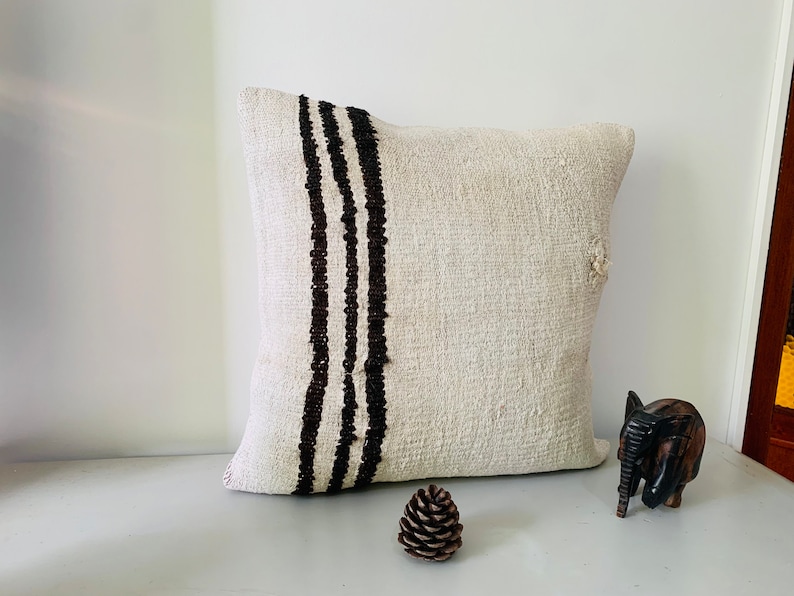 May include: A white throw pillow with black stripes down the side. The pillow is made of a soft, textured fabric.