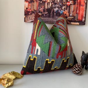 May include: A blue, red, green, and black patterned throw pillow with a geometric design. The pillow is made of woven fabric and has a square shape.