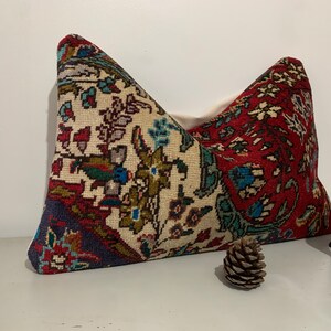 Puede incluir: Una almohada decorativa con un estampado floral colorido sobre un fondo blanco. La almohada est&aacute; hecha de una tela tejida y tiene un esquema de color rojo, azul y verde.