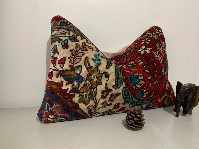 Puede incluir: Una almohada decorativa con un estampado floral colorido sobre un fondo blanco. La almohada est&aacute; hecha de una tela tejida y tiene un esquema de color rojo, azul y verde.