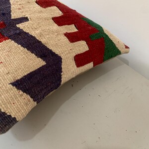 May include: A cream-colored throw pillow with a geometric pattern in red, green, and blue.