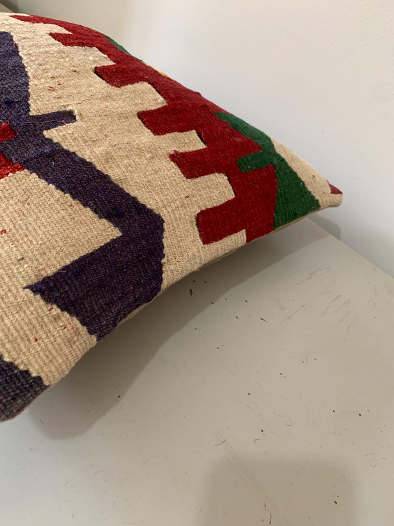 May include: A cream-colored throw pillow with a geometric pattern in red, green, and blue.