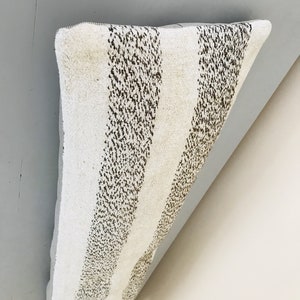 May include: A white and brown striped pillow with a textured surface.
